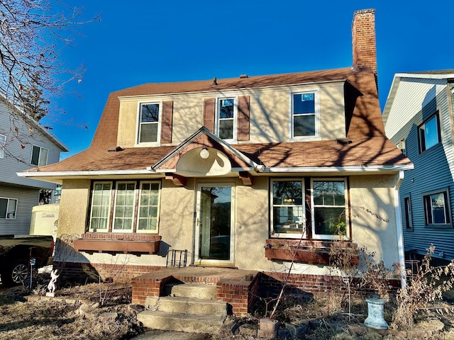 view of front facade featuring a chimney and stucco siding