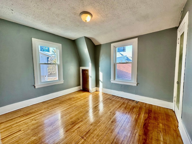bonus room featuring baseboards, a healthy amount of sunlight, and light wood-style floors