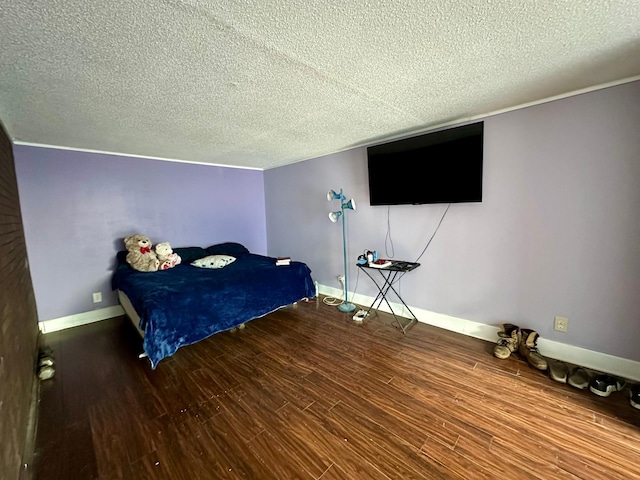 bedroom featuring a textured ceiling, baseboards, and wood finished floors