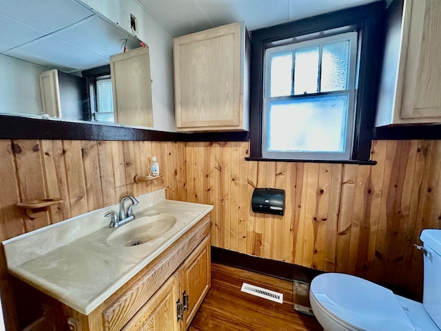 bathroom featuring toilet, wood finished floors, visible vents, and wooden walls