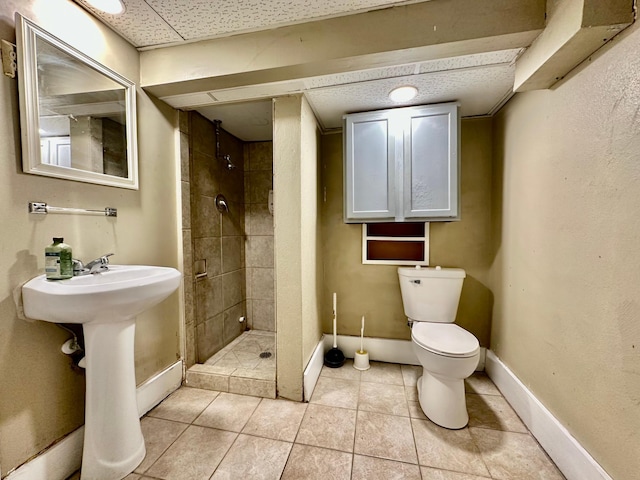 bathroom with toilet, a stall shower, tile patterned flooring, and baseboards
