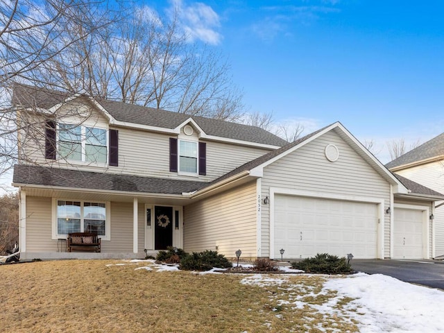 traditional-style house with a garage, covered porch, a shingled roof, and aphalt driveway