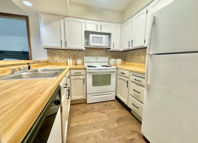 kitchen featuring white appliances, white cabinetry, a sink, and decorative backsplash