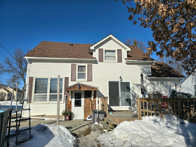 snow covered rear of property featuring roof with shingles and a wooden deck