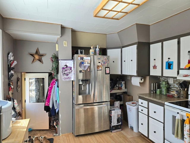 kitchen with white electric range oven, stainless steel fridge, white cabinets, dark countertops, and light wood-type flooring