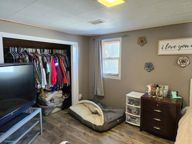 bedroom with a closet, wood finished floors, and visible vents