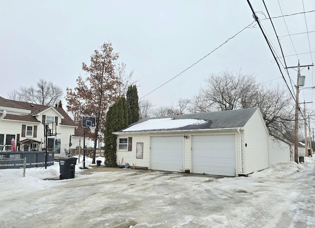 snow covered garage with a garage and fence