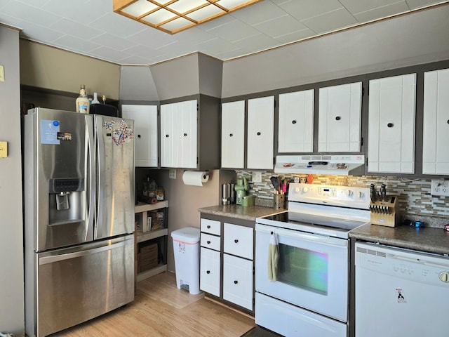 kitchen featuring white appliances, range hood, white cabinets, and tasteful backsplash