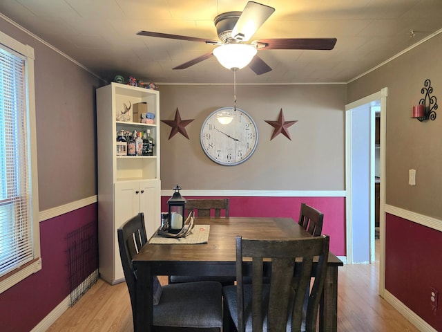dining space with wood finished floors, ceiling fan, ornamental molding, and baseboards