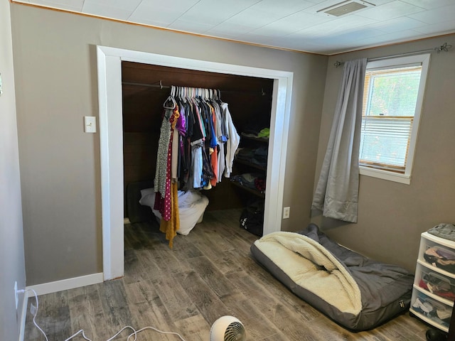 bedroom with wood finished floors and a closet