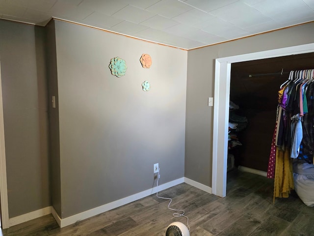 unfurnished bedroom featuring wood finished floors, a closet, and baseboards