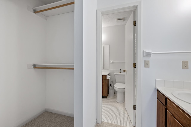 bathroom featuring a textured ceiling, toilet, vanity, and tile patterned floors