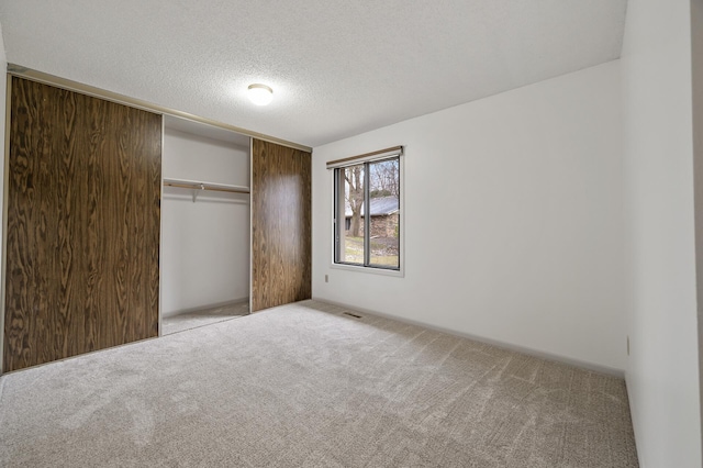 unfurnished bedroom with light carpet, a closet, and a textured ceiling