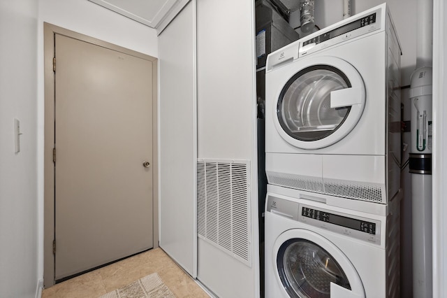 clothes washing area with stacked washer and dryer, light tile patterned floors, and laundry area