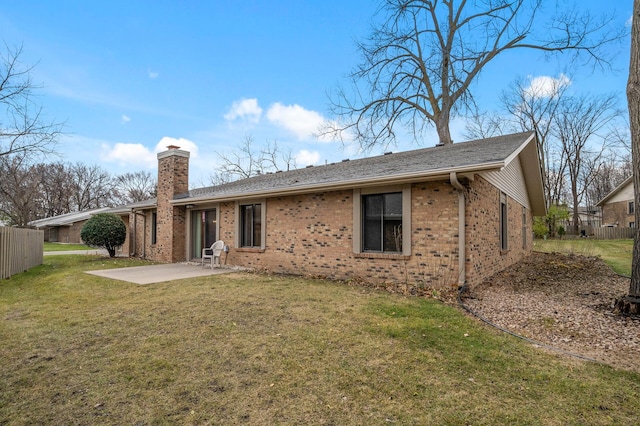 back of house featuring a yard, a patio area, a chimney, and brick siding