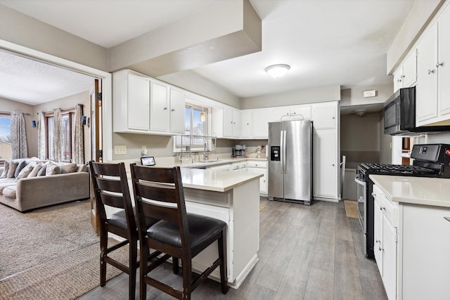 kitchen with stainless steel appliances, open floor plan, light countertops, and white cabinetry