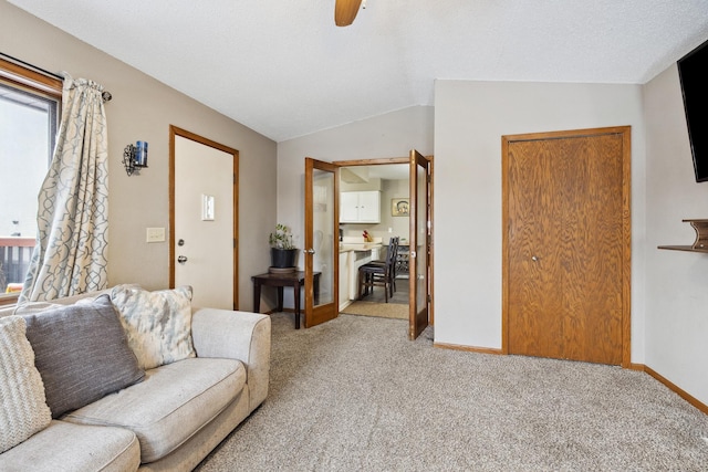 carpeted living room featuring lofted ceiling, ceiling fan, and baseboards