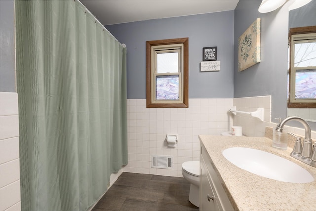 full bath featuring a healthy amount of sunlight, visible vents, toilet, and tile walls