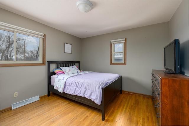 bedroom featuring baseboards, visible vents, light wood finished floors, and multiple windows