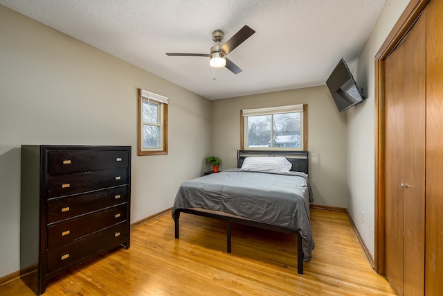 bedroom featuring a textured ceiling, light wood-style flooring, and baseboards