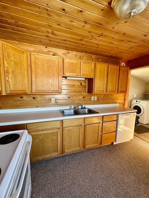 kitchen with washer / dryer, white range with electric stovetop, light countertops, and a sink