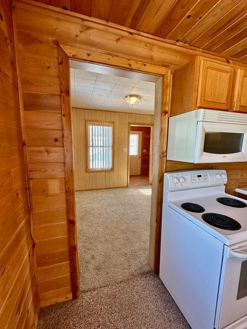 kitchen with wooden ceiling, white appliances, carpet flooring, and wood walls