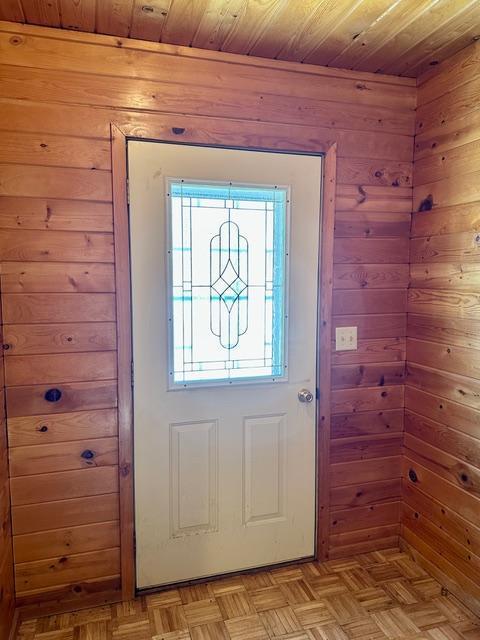 doorway with wooden ceiling and wood walls