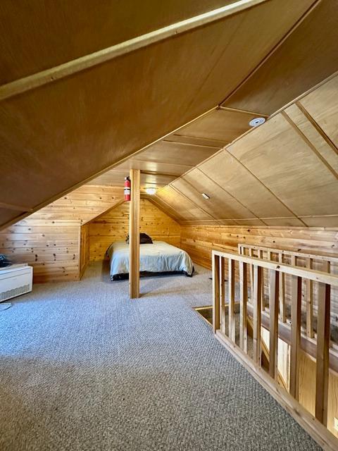 bonus room featuring wooden walls, vaulted ceiling, and carpet flooring