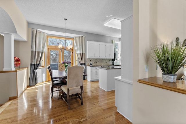 dining room featuring a chandelier, a textured ceiling, and light wood-style flooring