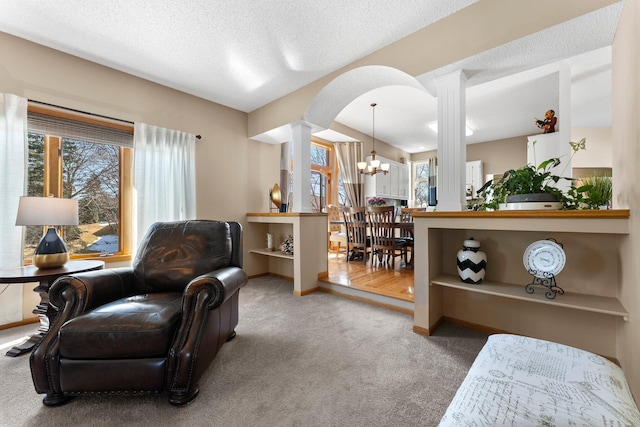 living area with a healthy amount of sunlight, carpet floors, and a chandelier