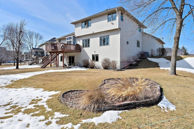 snow covered rear of property with a deck, central air condition unit, stairs, and a yard