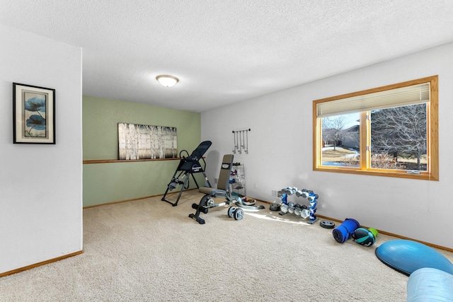 workout area with carpet, baseboards, and a textured ceiling