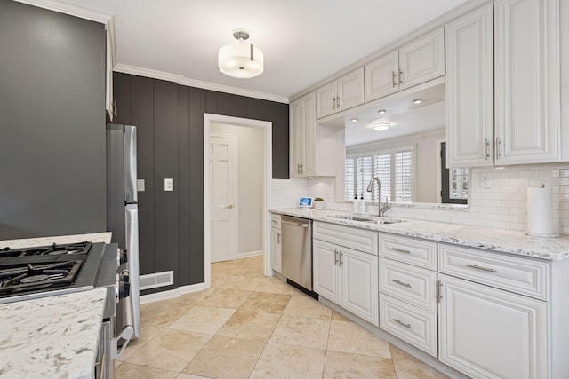 kitchen featuring stainless steel appliances, white cabinetry, a sink, and ornamental molding