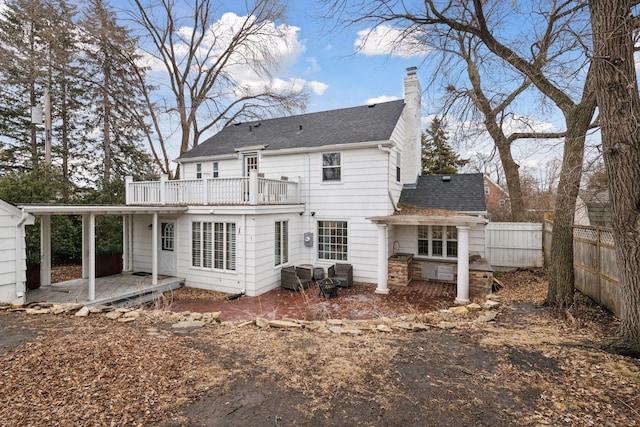 rear view of property with a shingled roof, a chimney, and fence