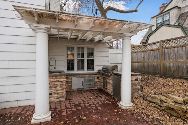 view of patio featuring a sink, an outdoor kitchen, fence, and area for grilling