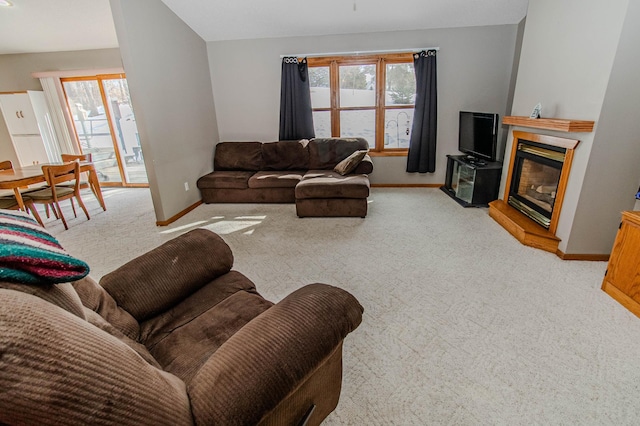 living room with a glass covered fireplace, light colored carpet, and baseboards