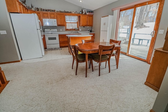 dining room featuring lofted ceiling and light colored carpet