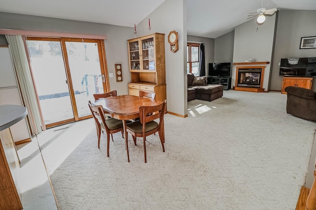 dining space featuring a glass covered fireplace, carpet flooring, ceiling fan, and lofted ceiling