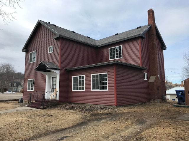 exterior space featuring a chimney and roof with shingles