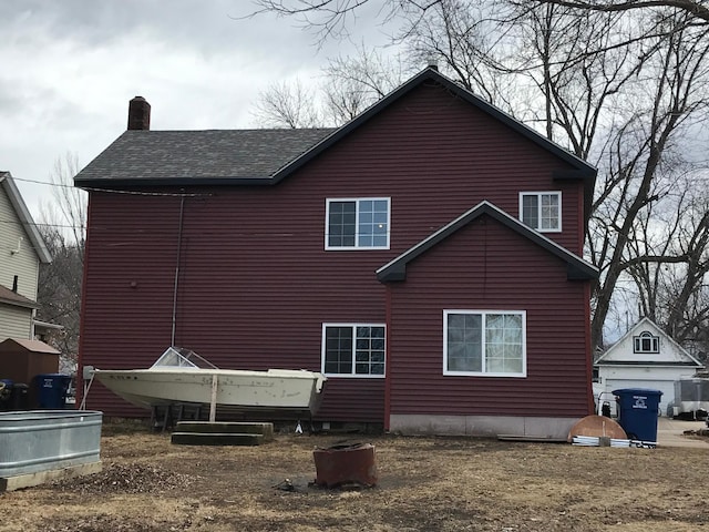 rear view of property featuring roof with shingles and a chimney