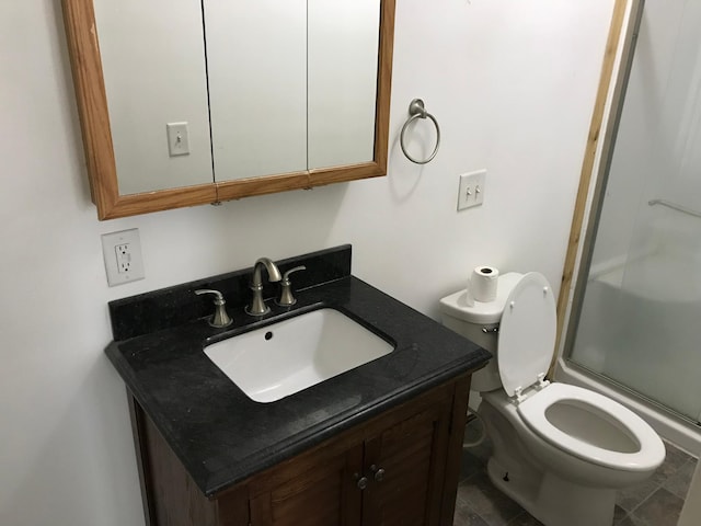 full bathroom with toilet, vanity, and a shower with shower door