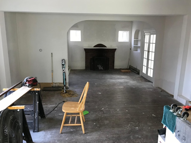 living area featuring arched walkways, a fireplace, and wood finished floors