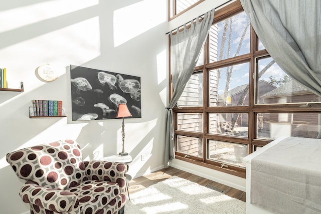 sitting room with a high ceiling, wood finished floors, visible vents, and baseboards