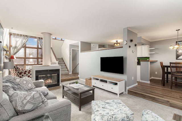 living room with light wood-style flooring, baseboards, stairway, a glass covered fireplace, and an inviting chandelier