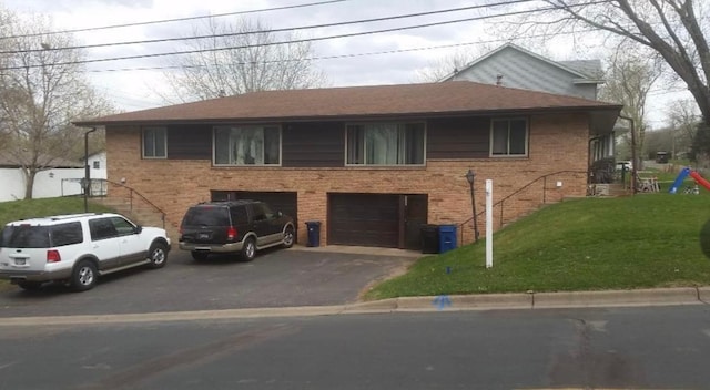 view of front of house featuring aphalt driveway, a front yard, brick siding, and an attached garage