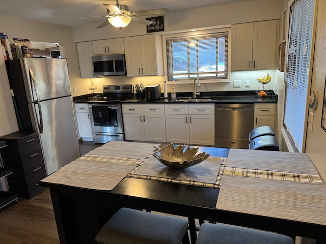 kitchen with stainless steel appliances, dark countertops, white cabinets, and a sink