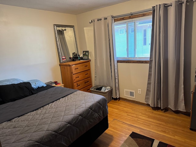 bedroom featuring wood finished floors and visible vents