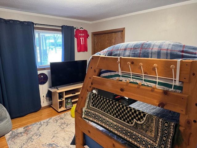 bedroom with ornamental molding, a textured ceiling, and wood finished floors