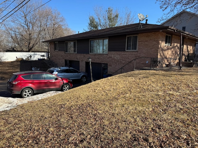 view of front facade with a garage, brick siding, a front lawn, and fence