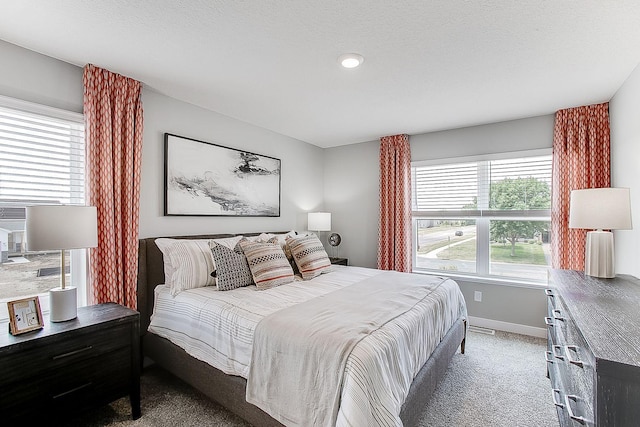 carpeted bedroom with visible vents, a textured ceiling, and baseboards